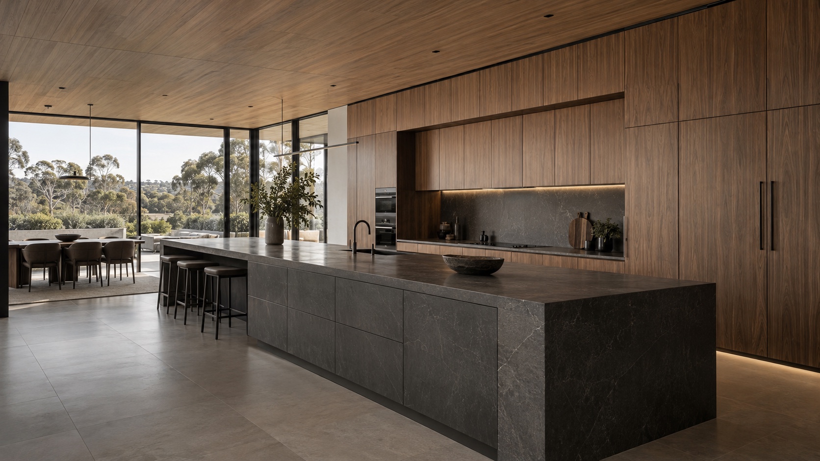 Grand villa kitchen concept with a long stone island, full-height timber cabinetry and eucalyptus garden views